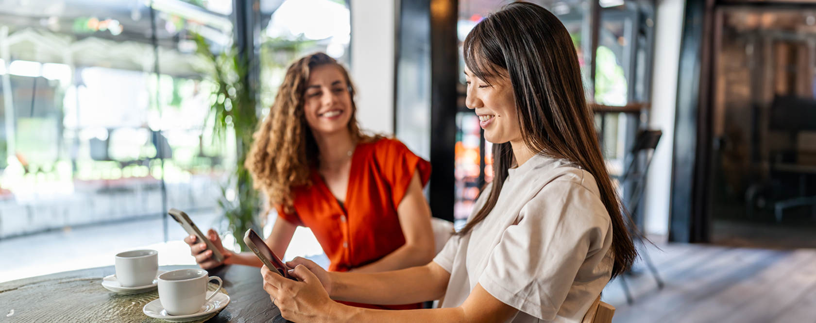 Two women sitting in a cafe using Zelle